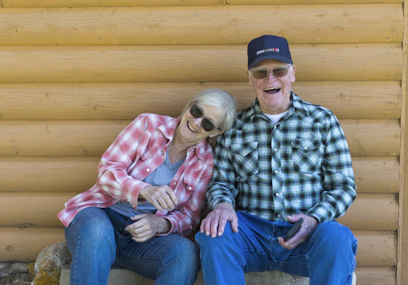 Older Australian couple sitting together outdoors, smiling and enjoying each other's company