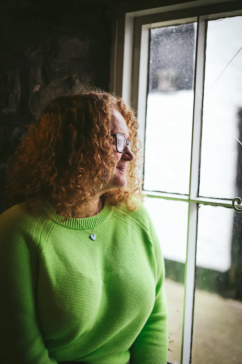 Senior sitting alone by a window, representing the challenge of loneliness among older Australians