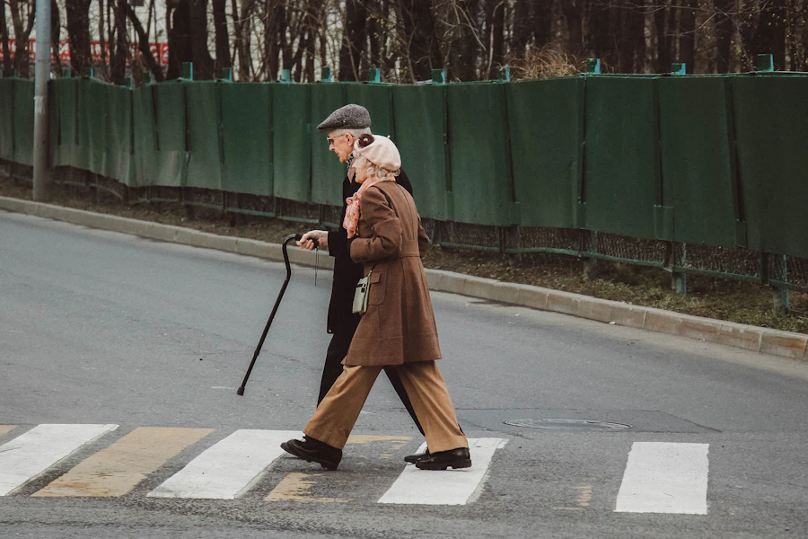 Elderly person walking carefully and confidently with a cane on a footpath