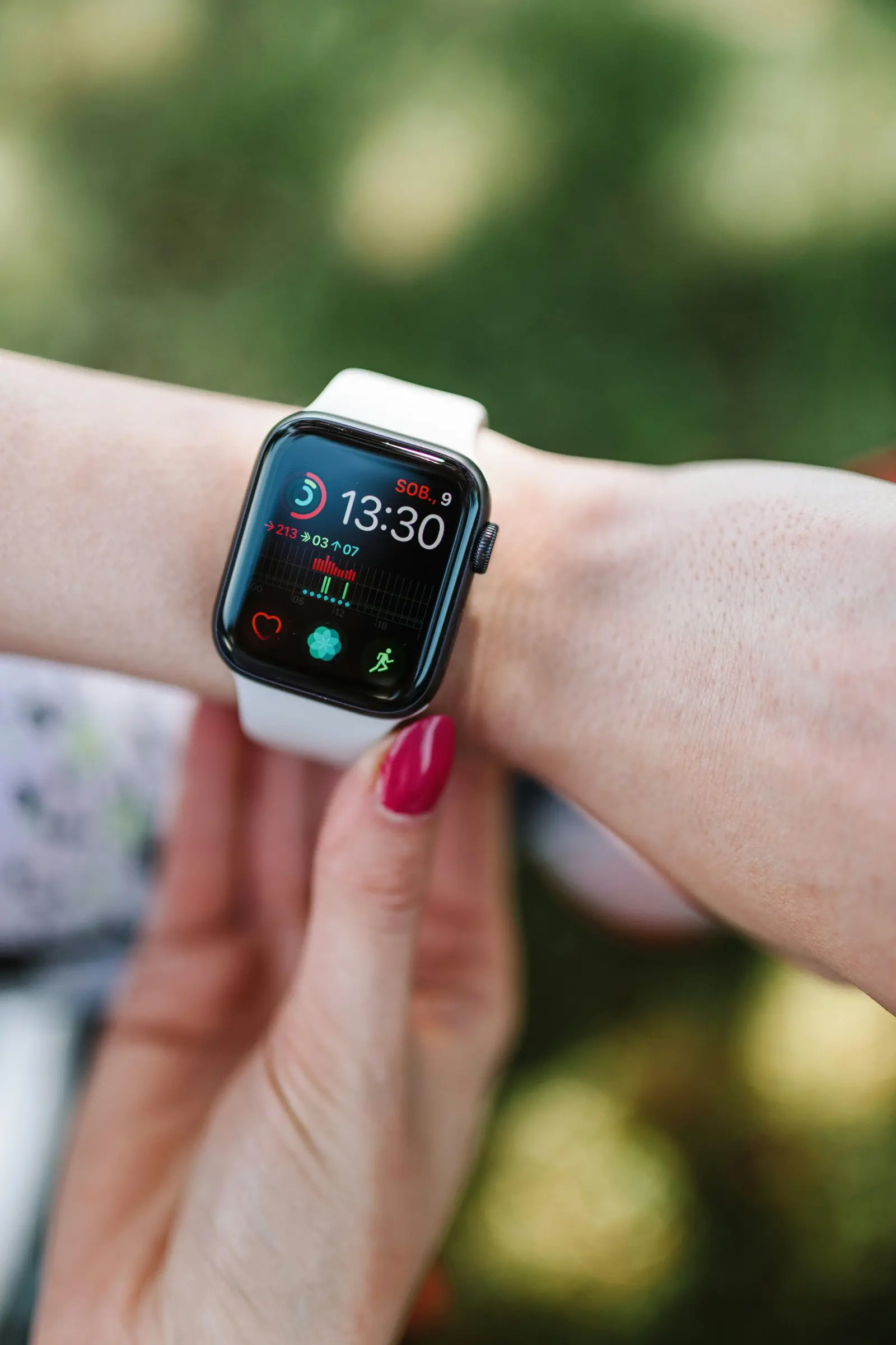 Close-up of a smartwatch displaying fitness data on a person's wrist outdoors