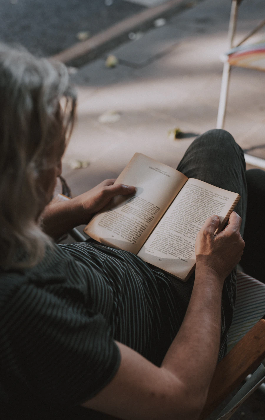 Older person reading a book thoughtfully in a comfortable indoor setting