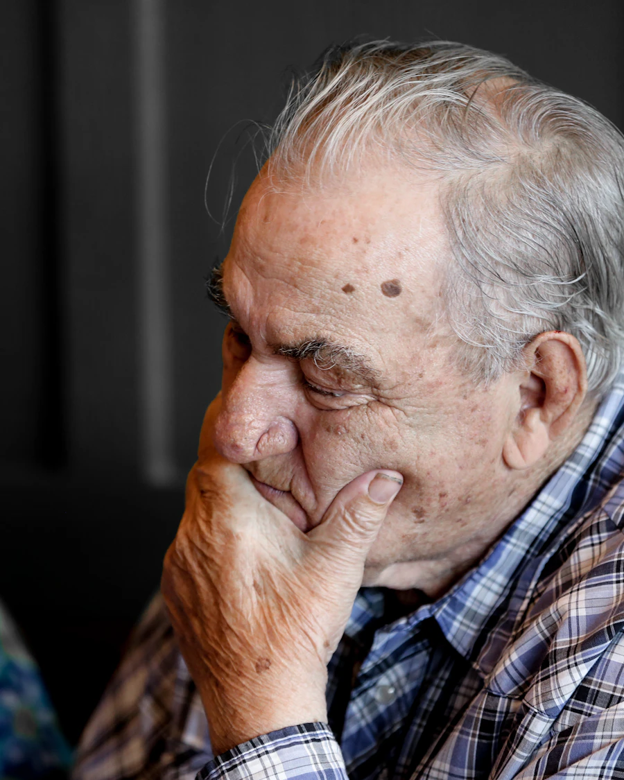 Senior person sitting thoughtfully in a garden, contemplating the difference between normal forgetting and dementia