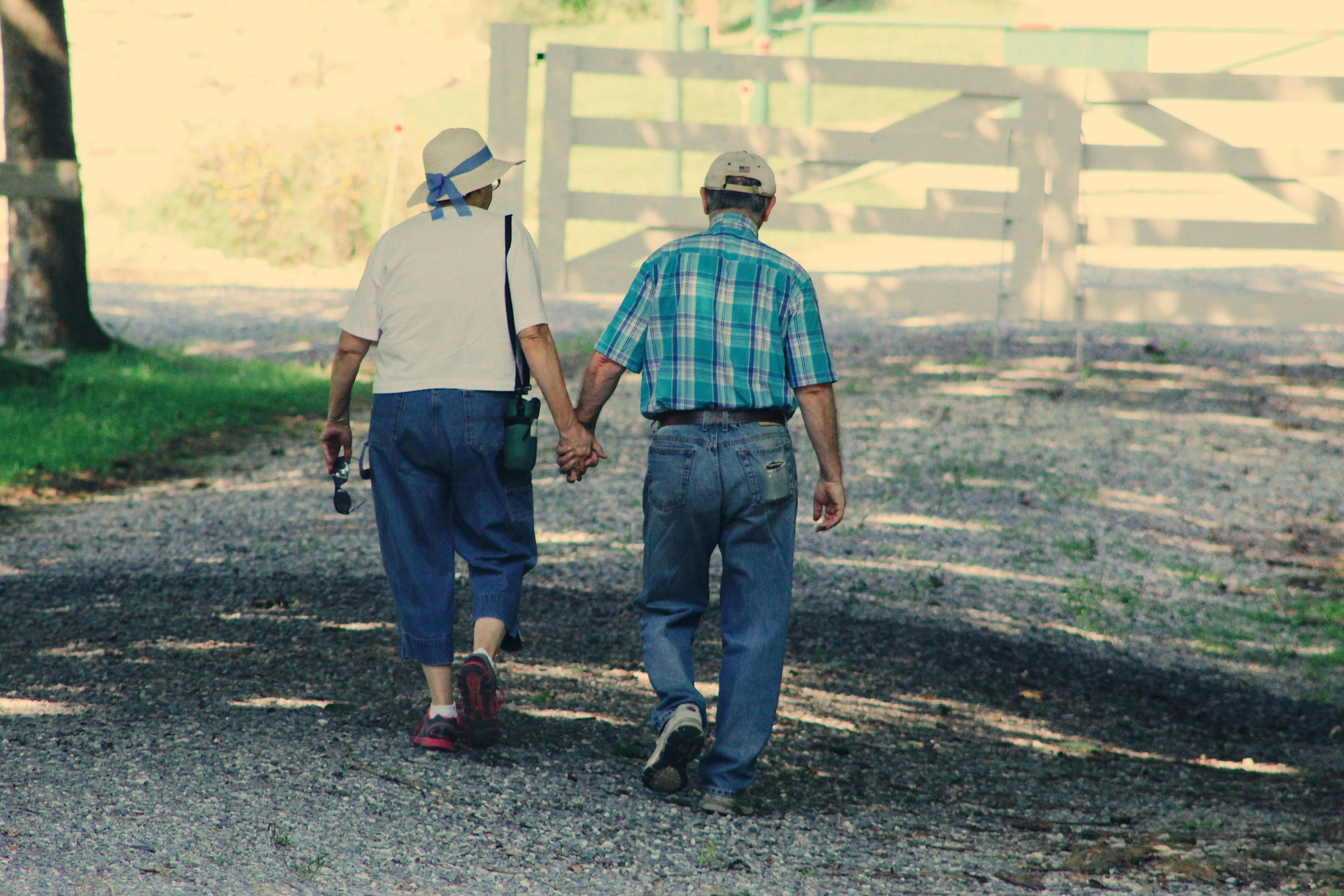 Senior couple holding hands walking together on a gravel path outdoors
