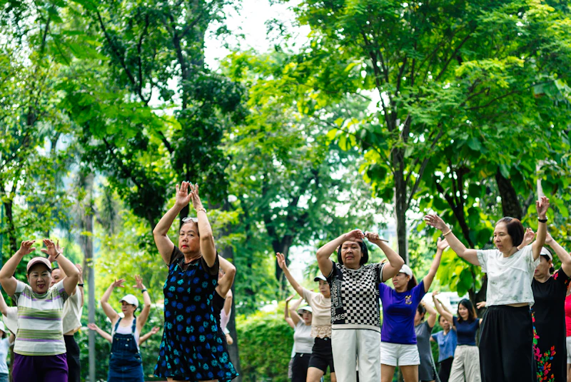 Group of older adults doing yoga and gentle exercises together outdoors in a park setting
